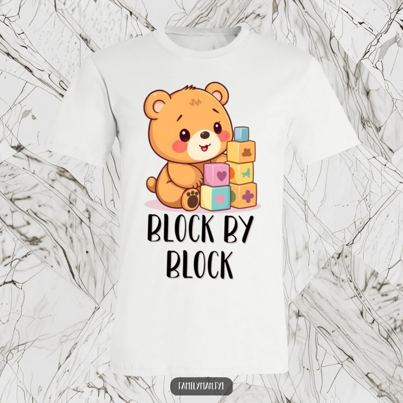 Funny t-shirt graphic of a happy bear cub intently stacking colorful wooden blocks with a smile.